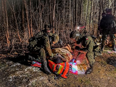 Polish servicemen deliver medical support and transport a migrant on the border with Belarus. Reuters 