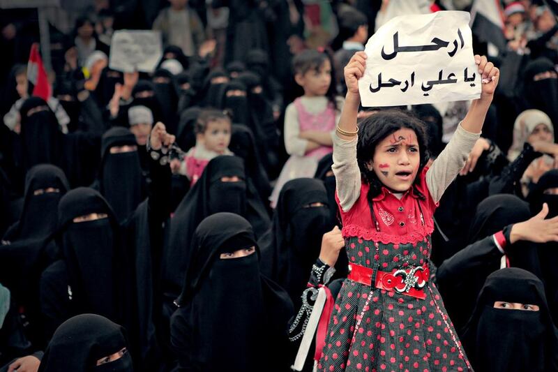 A girl holds a sign reading “Leave, Ali, Leave” in Karama Has No Walls. Courtesy Sara Ishaq

