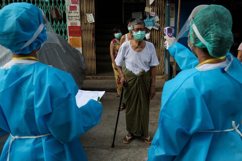 A medical staff member wearing protective gear amid concerns over the spread of the COVID-19 coronavirus takes the temperature of a resident while going door-to-door for health check-ups in Yangon.  AFP