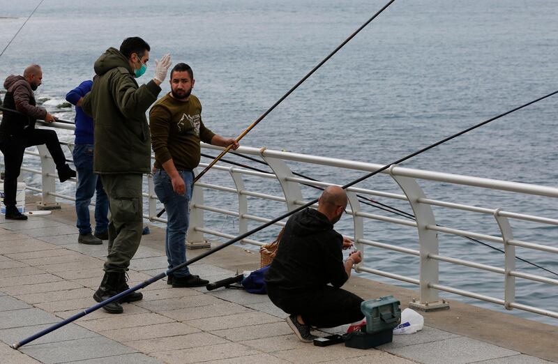 A municipal policeman, left, orders fishermen to leave the corniche, or waterfront promenade, along the Mediterranean Sea, as the country's top security council and the government were meeting over the spread of coronavirus, in Beirut, Lebanon. AP Photo