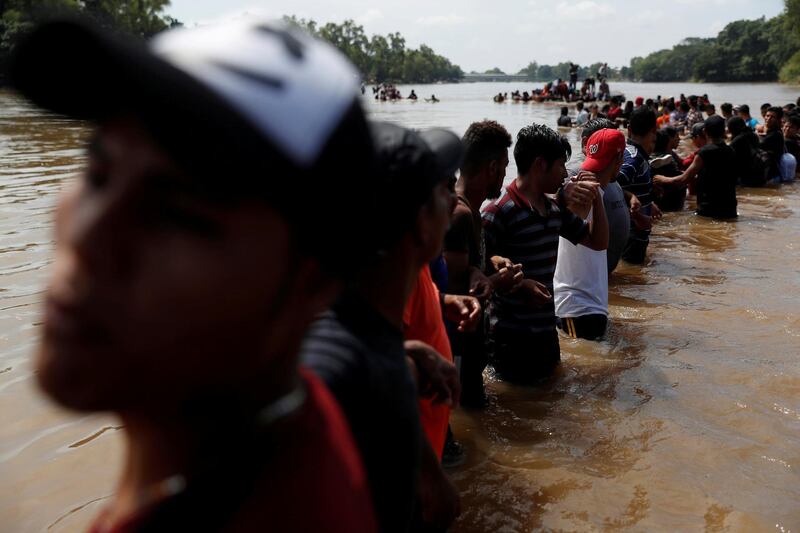 Migrants form a human chain to help fellow migrants cross the Suchiate river. Reuters