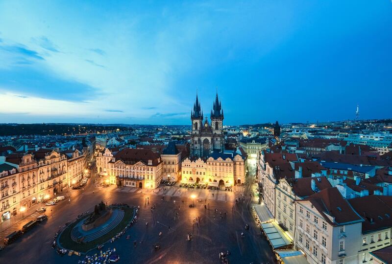 Wide angle image of Prague's Old Town Square (Stare mesto) with Tyn Cathedral Gothic spires in the center, all illuminated at dusk in Prague, Czech republic, a UNESCO heritage site