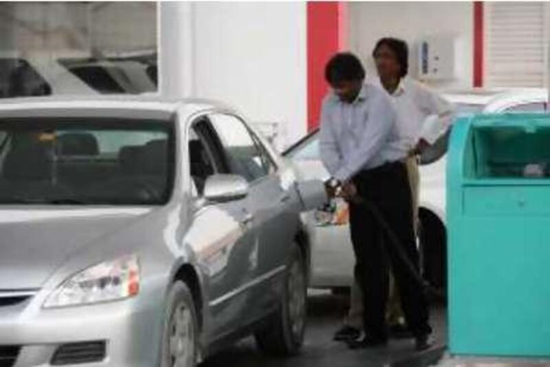 DUBAI, UNITED ARAB EMIRATES - August 12:  Charles Kenneth (left), a businessman who lives in Sharjah, pumping petrol at the Enoc Petrol station off Jumeirah Beach Road in Dubai on August 12, 2008.  Enoc has introduced a trial period whereby customers must first pay for their petrol upfront and then pump it themselves. They were not offering an incentive for people to pump their own petrol as they do in other countries and reactions to this trial were negative.  (Randi Sokoloff / The National) *** Local Caption ***  RS007-ENOC.jpgRS007-ENOC.jpg