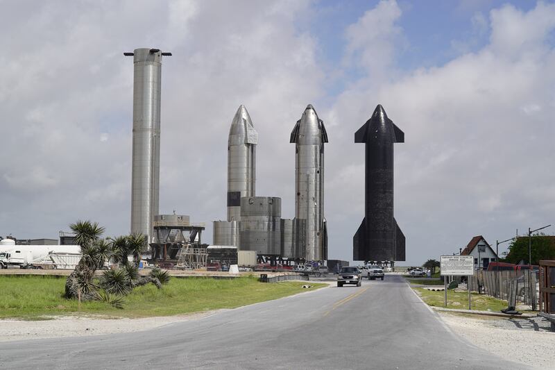Three Starship rockets stand next to a booster. The reusable rockets are at the centre of SpaceX's plans for the future. 