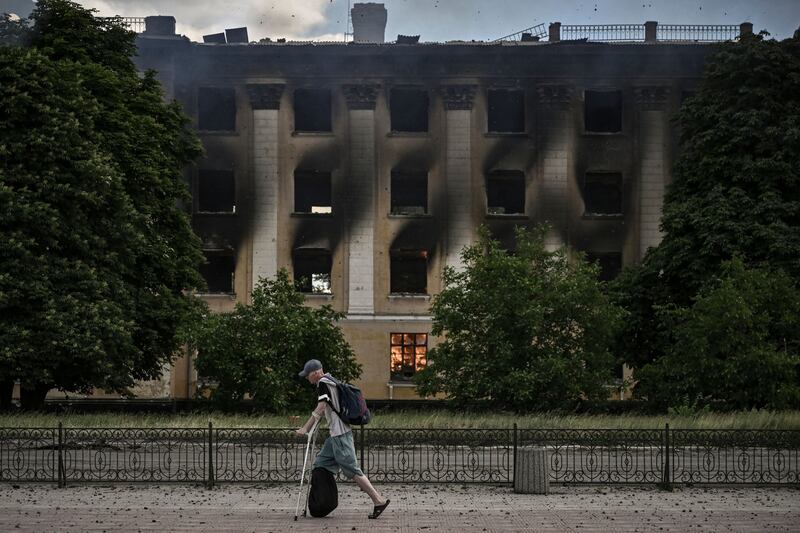 A man walks past a college on fire after a strike in Lysychansk in the eastern Ukrainian region of Donbas. AFP