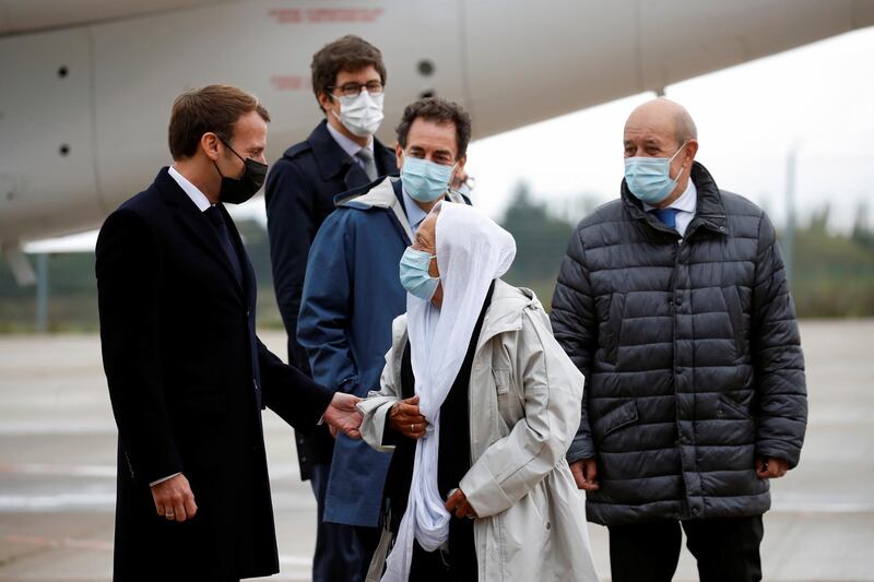 French President Emmanuel Macron, left, and French Foreign Minister Jean-Yves Le Drian, right, welcome Sophie Petronin, center, a French aid worker held hostages for four years by Islamic extremists in Mali, upon her arrival at the Villacoublay military airport near Paris, Friday Oct. 9, 2020. Sophie Petronin was released with three other hostages from Mali and Italy this week. Before leaving Mali's capital, she said she was doing well and wanted to return to Mali to resume her humanitarian work with malnourished children and orphans.(Gonzalo Fuentes, Pool Photo via AP)