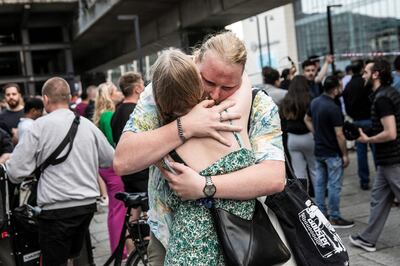 People hug each other in front of the Field's shopping mall in Copenhagen, where a gunman killed three people. AFP