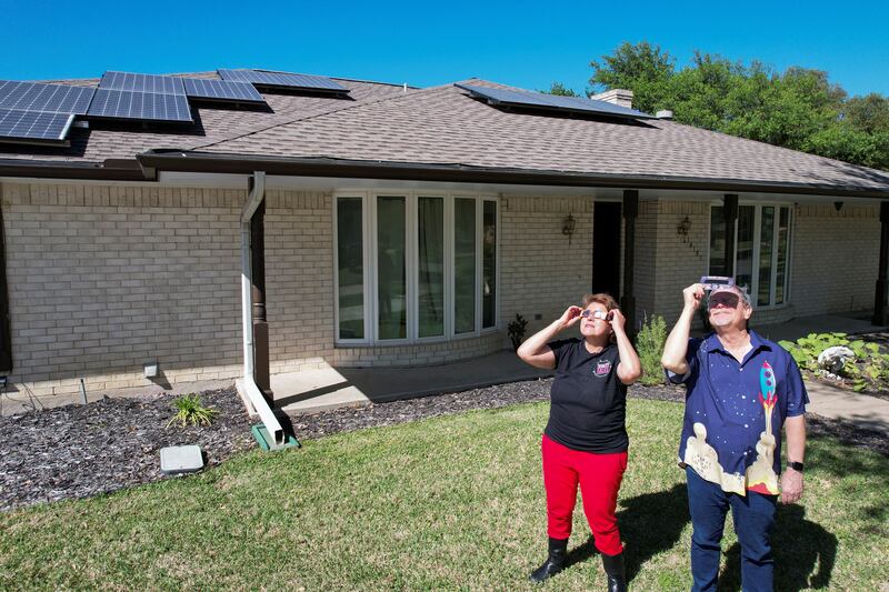 Eclipse chaser Leticia Ferrer and her husband Daniel Brookshier observe the sun through eclipse glasses, in front of their home in Dallas, Texas, U. S. , April 3, 2024.  REUTERS / Evan Garcia