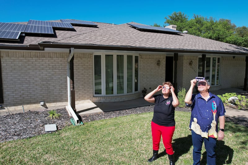 A couple observe the sun through eclipse glasses in front of their home in Dallas, Texas. Reuters