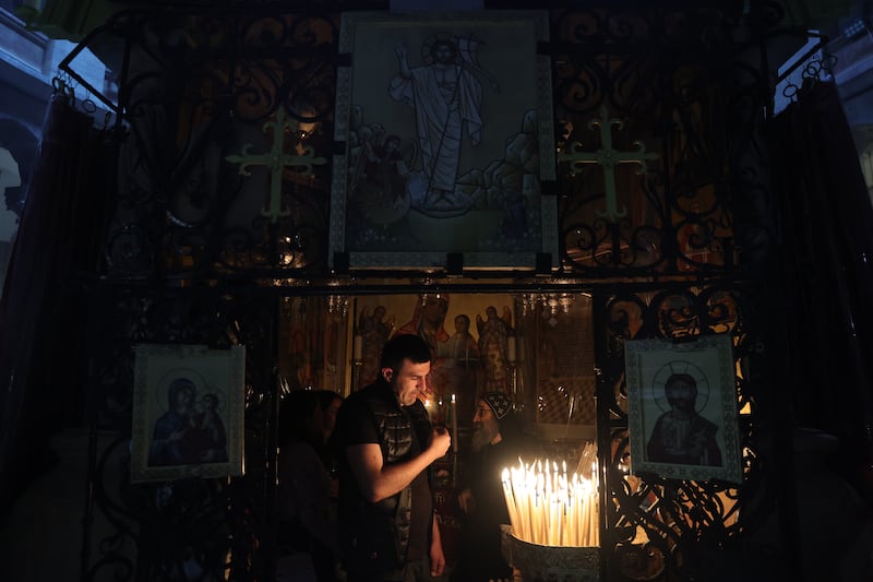 A worshipper lights a candle during the Good Friday procession at the Church of the Holy Sepulchre in the Old City of Jerusalem. EPA