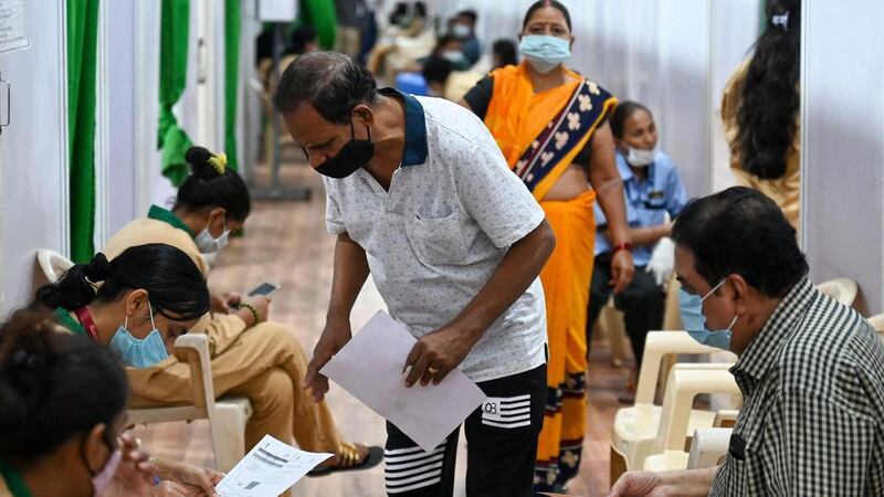 People fill out personal information forms before getting inoculated against Covid-19 at a vaccination centre in Mumbai. AFP