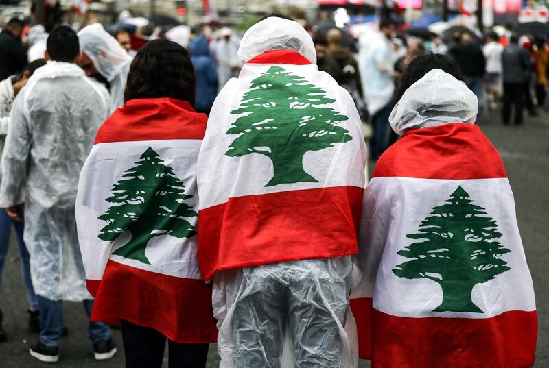 Protesters wearing ponchos and draped with the Lebanese national flag stand under the rain in Zouk Mosbeh, north of the capital Beirut. AFP