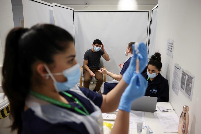 A person waits to get the vaccine as a health worker prepares an injection with a dose, at a vaccination centre in Westfield Stratford City shopping centre, London. Reuters
