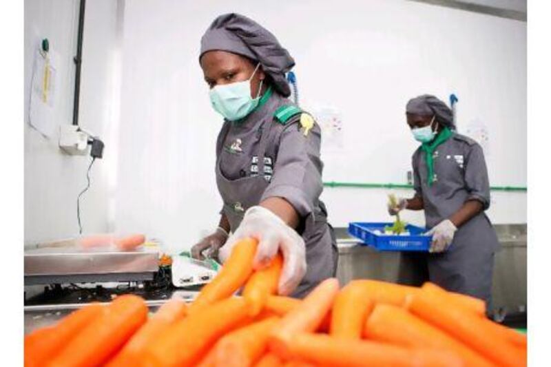Chef Phelistas Vunya, left, and kitchen hand Farouk Mutebi get to work at Food Pro Solutions' industrial kitchen in Jebel Ali, Dubai. Callaghan Walsh / The National