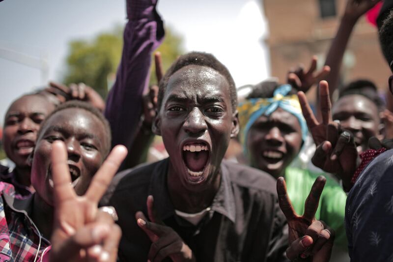 Sudanese men celebrate outside the Friendship Hall in the capital Khartoum where generals and protest leaders signed a historic transitional constitution meant to pave the way for civilian rule in Sudan.  AFP