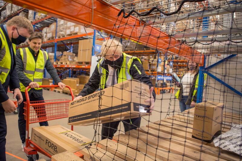 Boris Johnson helps to lift boxes in the warehouse. AP Photo