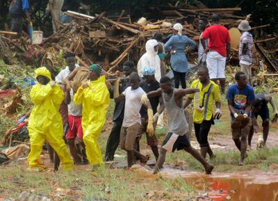 Rescue workers carry the body of a victim from the site of a mudslide in Regent, east of Freetown, Sierra Leone, Monday, Aug. 14, 2017. Mudslides and torrential flooding has killed many people in and around Sierra Leone's capital early Monday following heavy rains, with many victims thought to be trapped in homes buried under tons of mud. (AP Photo/ Manika Kamara)
