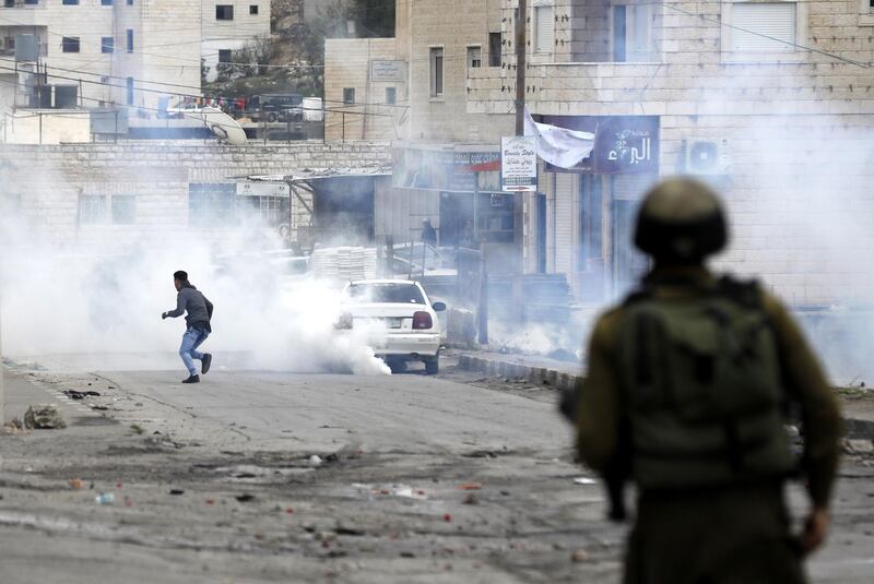 epa06411060 A Palestinian runs from tear gas during clashes in al-Fawwar refugee camp, south of the West Bank city of Hebron, 31 December 2017. Clashes erupted as ongoing protests were held against US President Trump's 06 December announcement he is recognizing Jerusalem as the Israel capital and will relocate the US embassy from Tel Aviv to Jerusalem.  EPA/ABED AL HASHLAMOUN