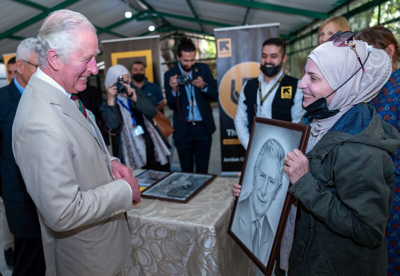 Prince Charles chuckles as a woman shows a portrait of him, during a visit to the UNHCR Community Support Centre in Al Nuzha, Jordan. Reuters