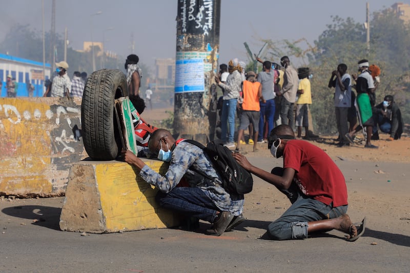 Sudanese protesters take cover during clashes with security forces at an anti-coup protest, in Khartoum, Sudan, 09 January 2022.  Security forces fired tear gas to disperse protesters gathering in Khartoum and attempting to march towards the presidential palace, as part of the continuing protesting movement against a military coup in October 2021.  The protest was organized a day after the UN envoy for Sudan said the international group will invite different parties for talks in Sudan to end the crisis.  EPA