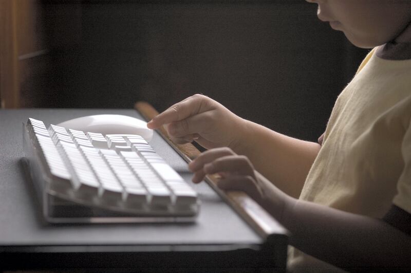 Child about to touch the computer keyboard.