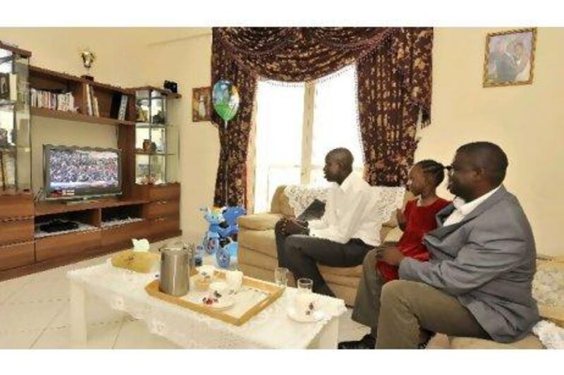 Left to right, the South Sudanese expatriates Bona Rehan and Gloria and Kennedy Danga watch news coverage of the nation's birth on television yesterday. Charles Crowell for The National