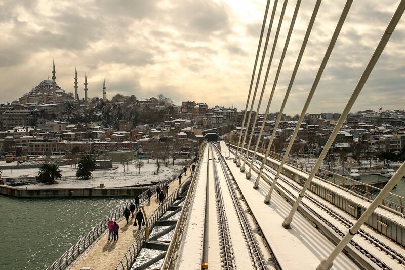 People walk over the Golden Horn with Suleymaniye Mosque in the background in Istanbul. AP