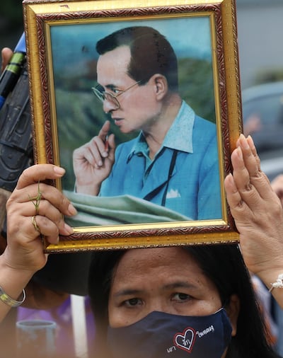 epa08689765 A Royalist and pro-government supporter holds a photograph of the late Thai King Bhumibol Adulyadej, during a rally held to show opposition to any amendments to the constitution, outside the Parliament House, in Bangkok, Thailand, 23 September 2020. The parliament of Thailand will hold special sessions from 23 to 24 September 2020 to deliberate charter amendment proposals and the establishment of a charter drafting group.  EPA/NARONG SANGNAK