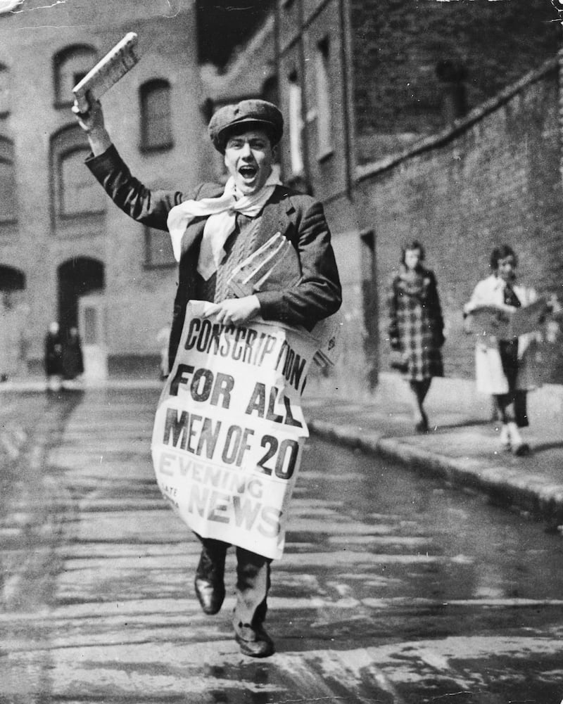 A newspaper boy with a poster calling for the conscription of all 20-year-old men in 1939