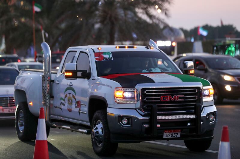 A pickup truck decorated with the UAE flag colours drives along the Corniche in Abu Dhabi. Khushnum Bhandari / The National