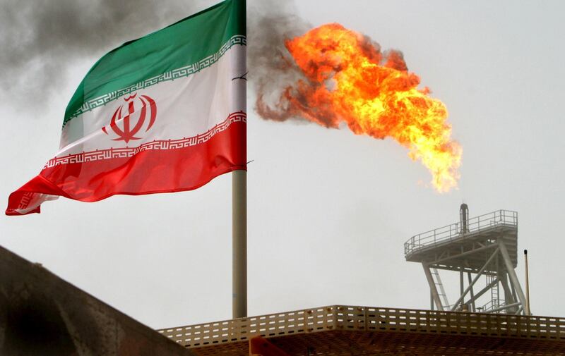 FILE PHOTO: gas flare on an oil production platform in the Soroush oil fields is seen alongside an Iranian flag in the Gulf July 25, 2005. REUTERS/Raheb Homavandi/File Photo