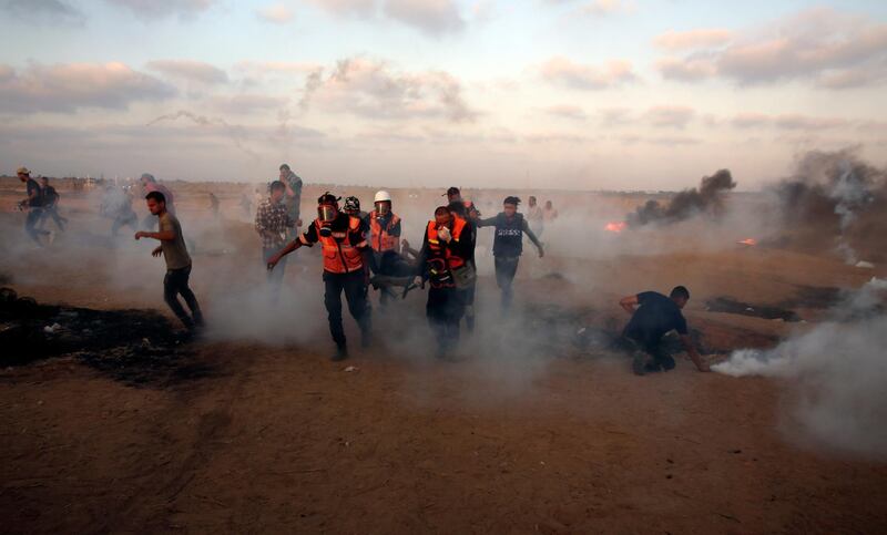 Medics evacuate a wounded youth while others run to cover from teargas fired by Israeli troops near the Gaza Strip border with Israel, during a protest east of Khan Younis, southern Gaza Strip, Friday, Aug. 24, 2018. The Gaza health ministry says Israeli gunfire wounded 50 Palestinians protesting along the border with Israel, and scores were treated for tear gas inhalation. Approximately 5,000 Gazans attended Friday's march, the lowest turnout in months of weekly protests organized by the Islamist militant group Hamas. (AP Photo/Adel Hana)