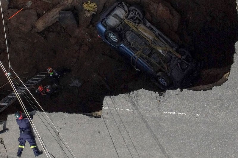 The three people were injured when their vehicle plunged into a sinkhole about 15 metres deep. They were rescued hours later by emergency services. AFP

