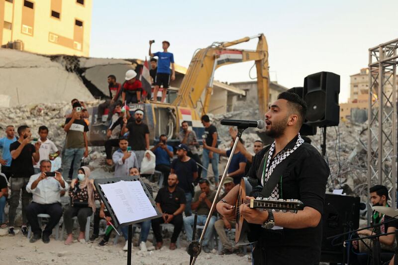 Musicians in Gaza city's Al Rimal neighbourhood perform in front of the remains of Al Shuruq Tower, which was levelled by an Israeli air strike during last month's conflict. AFP