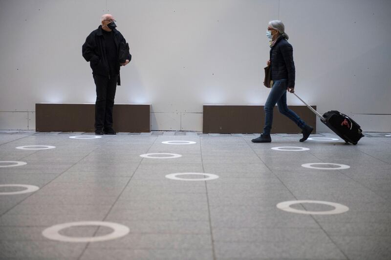 Commuters wearing protective face masks stand on social distance markers at Montparnasse train station in Paris. EPA