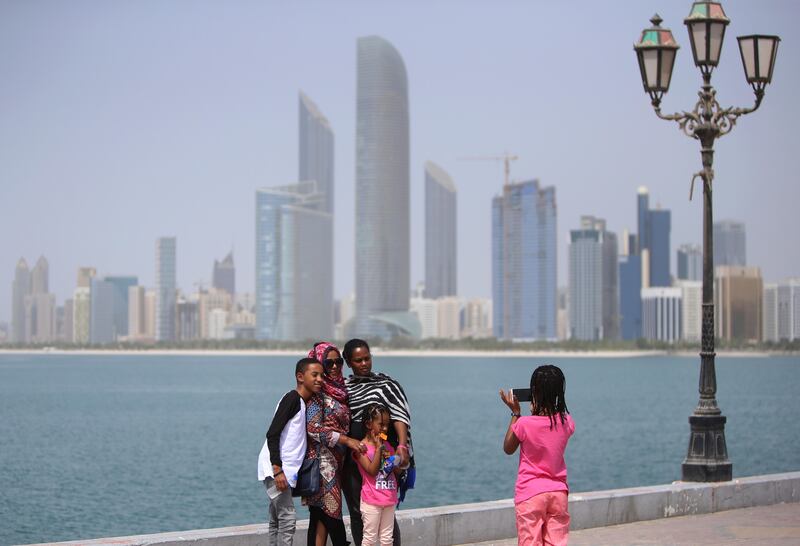 ABU DHABI - UNITED ARAB EMIRATES - 29JULY2016 - Visitors take quick selfies and photographs with Abu Dhabi skyline in the backdrop as the temperature scales 41 degree celsius with humidity showing 41 percentage at the breakwaters on the Corniche. Ravindranath K / The National (for Standalone) *** Local Caption ***  RK2907-STANDALONE02.jpg