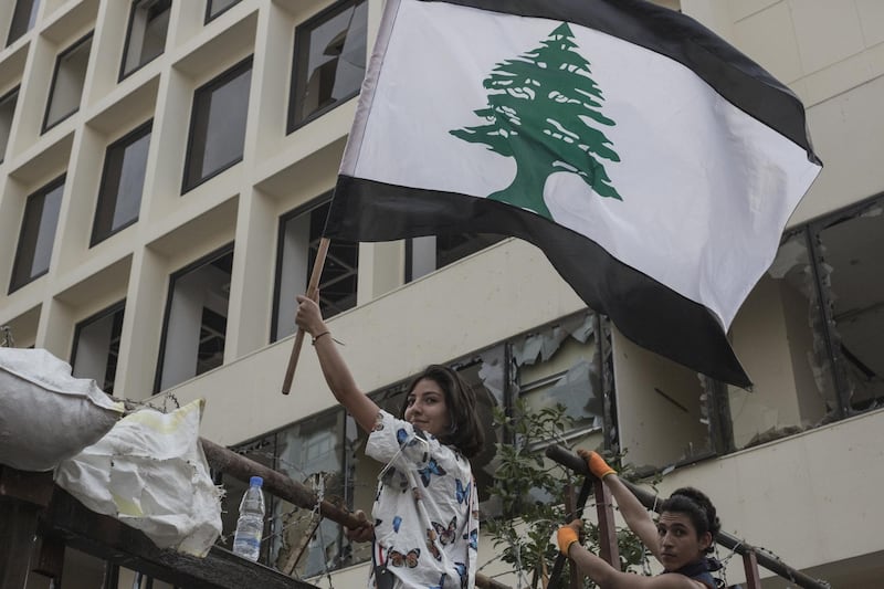 BEIRUT, LEBANON - SEPTEMBER 01: An anti government protester holds a Lebanese flag which has had the usual red stripes replaced with black as a sign of mourning, during a demonstration on September 1, 2020 in Beirut, Lebanon. This week, the country's political parties agreed in principle to form a new government under Mustapha Adib, Lebanon's former ambassador to Germany. The previous government resigned last month in the wake of the explosion in Beirut's port that killed more than 200 people and damaged large swaths of the city. (Photo by Sam Tarling/Getty Images)