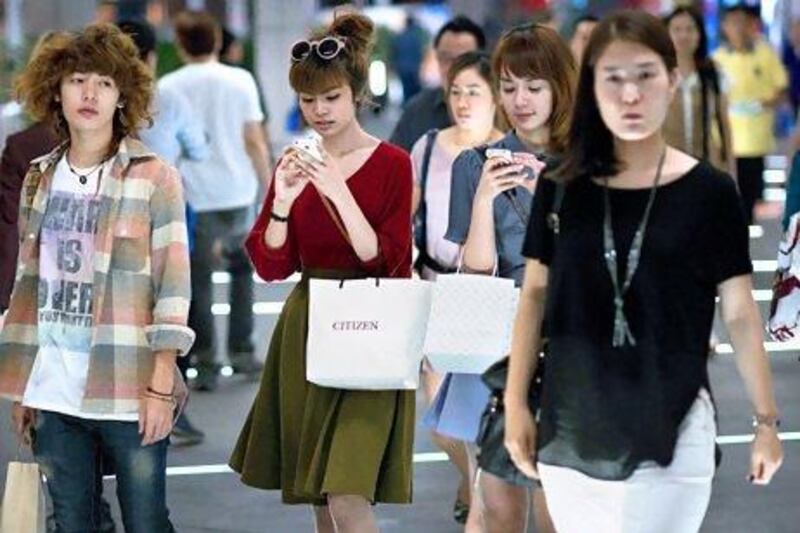 Shoppers use their smartphones in a Bangkok mall. Thai consumer confidence is at its highest since 2006. Nicolas Asfouri / AFP