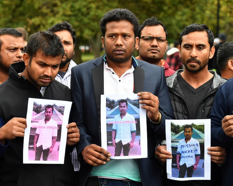 Friends of a missing man Zakaria Bhuiyan hold up photos of him outside a refuge centre in Christchurch. AAP Image via AP