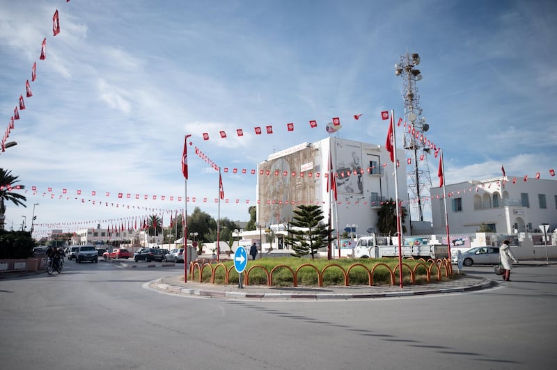 A roundabout in central Sidi Bouzid decorated with Tunisian flags. A giant mural of Mohamed Bouazizi can be seen in the background.