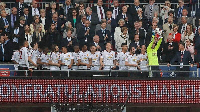 Manchester United’s Spanish goalkeeper David de Gea lifts the trophy as players celebrate their victory after extra time in the English FA Cup final football match between Crystal Palace and Manchester United at Wembley stadium in London on May 21, 2016. Manchester United won the game 2-1, after extra time. Adrian Dennis / AFP