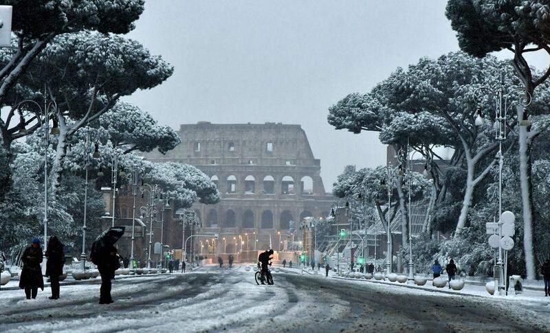 People walk in the snow near the Colosseum in Rome on February 26, 2018.  Tiziana Fabi / AFP