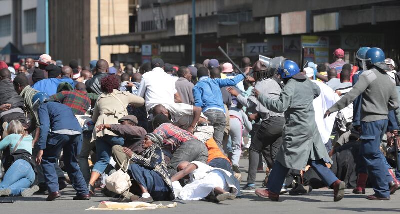 ZRP officers clash with members of the public who took part in the Peace March. EPA