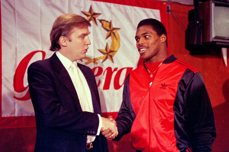 Former US president Donald Trump shakes hands with Herschel Walker after the US football player signed a four-year contract with the New Jersey Generals USFL football team. AP