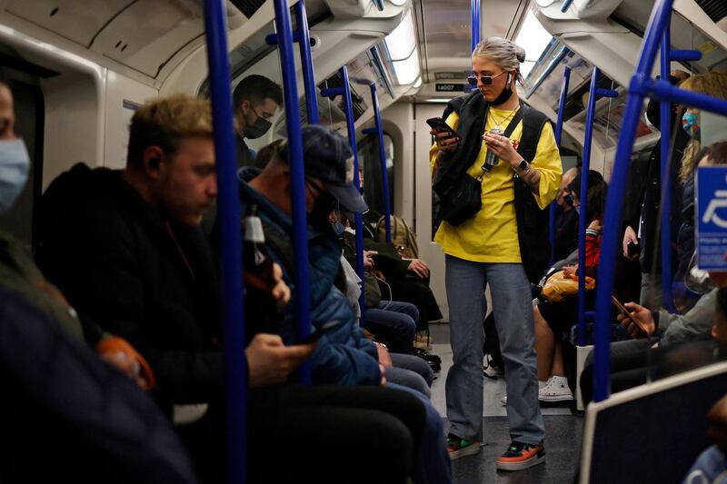 Passengers, some wearing protective face coverings and some not, travel on the London Underground. AFP