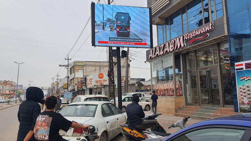 Basra residents watch the arrival of the Omani national team on a screen in the city