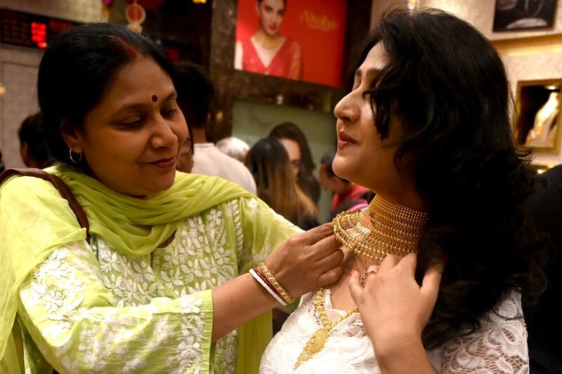 A female customer takes off a gold necklace after trying it at a Senco Gold & Diamonds jewellery showroom before  Diwali in Mumbai. AFP