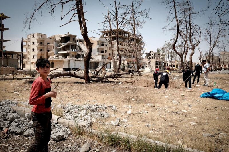 A boy watches firemen unearth corpses in Raqqa. Photo: David Pratt for The National