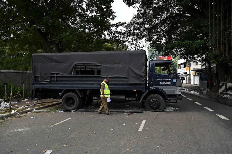 A security officer inspects a police vehicle, a day after it was vandalised by protesters in front of the residence of Sri Lanka's prime minister. AFP