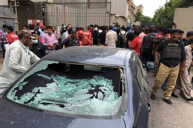 A plainclothes police officer, left, surveys the site of an attack at the Pakistan Stock Exchange entrance in Karachi on June 29, 2020. Reuters